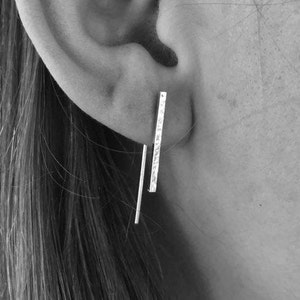 Puede incluir: Un par de pendientes de plata con una barra texturizada y una barra lisa.