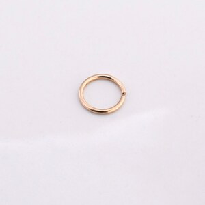 K&ouml;nnte beinhalten: Ein nahtloser Creolenohrring in Goldfarbe.