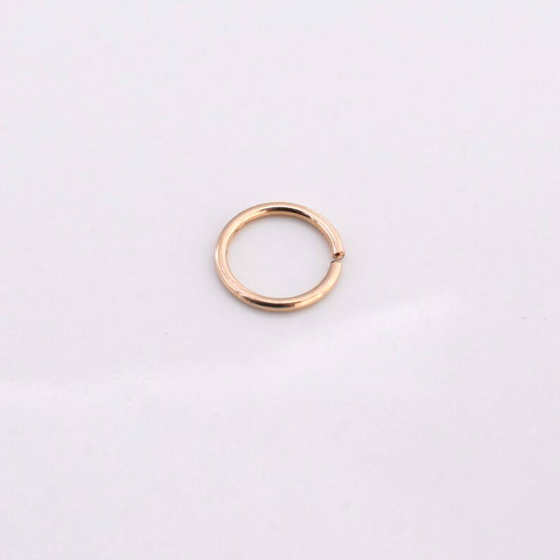 K&ouml;nnte beinhalten: Ein nahtloser Creolenohrring in Goldfarbe.