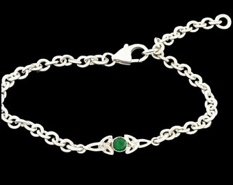 May include: A silver chain bracelet with a green gemstone set in a Celtic knot design.