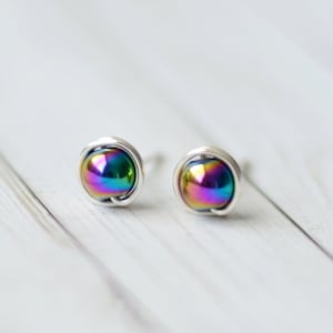 May include: A pair of silver stud earrings with iridescent rainbow colored round stones.