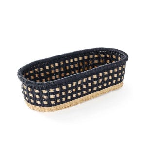 May include: Oval woven basket featuring a geometric pattern in black and tan. The basket has a dark navy blue rim and a natural tan base. This storage basket is suitable for various uses.