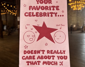 May include: Pink card with a red star and two cartoon faces. The text reads "YOUR FAVORITE CELEBRITY... DOESN'T REALLY CARE ABOUT YOU THAT MUCH :( by: Justine Veras"