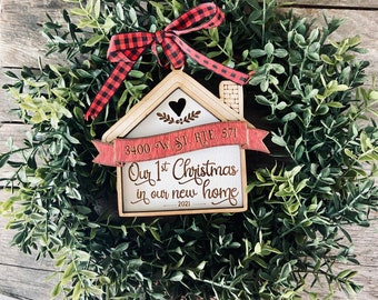 May include: A wooden house-shaped Christmas ornament with a red ribbon and the text "Our 1st Christmas in our new home 2021" and "3400 W. St. Rte. 571".