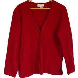 May include: A red cardigan sweater with a v-neck and button closure. The sweater is made of a soft, comfortable material.