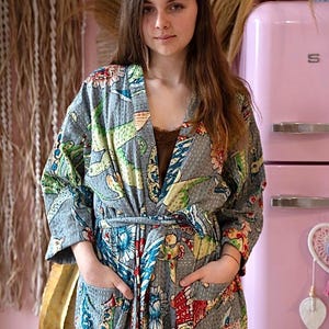 May include: A gray quilted robe with a floral and bird print. The robe has a tie belt and pockets.