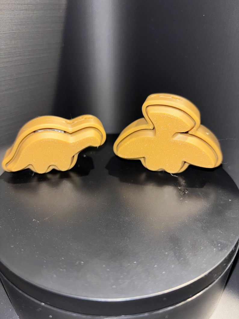 May include: Two brown cookie cutters, one shaped like a dinosaur and the other shaped like a bird.