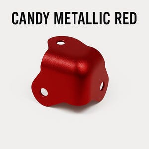 May include: A red metal corner protector with a candy metallic finish. The protector has three holes for attaching it to furniture.