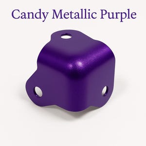 May include: A metallic purple corner brace with rounded edges and three holes. The brace is made of metal and has a shiny finish.