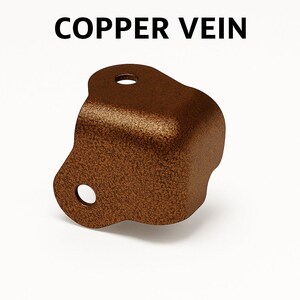May include: A copper-colored metal bracket with a textured finish. The bracket has two circular holes and the text "COPPER VEIN" in black letters above it. The bracket is designed with rounded edges and a curved shape.