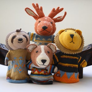 May include: Four knitted finger puppets, a deer, a sloth, a dog, and a lion, each wearing a different patterned sweater. The puppets are made by the brand "Gruno Chicco".