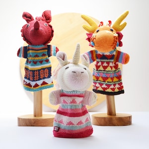 May include: Three knitted finger puppets, a red dragon, an orange dragon, and a pink unicorn. Each puppet is wearing a colorful, patterned sweater.