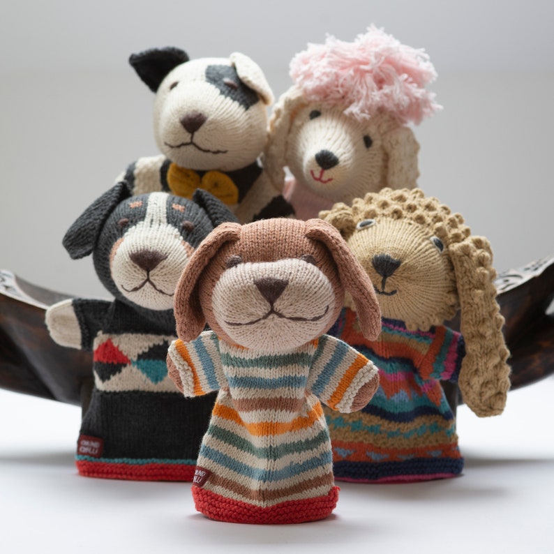 Pu&ograve; includere: Cinque marionette per dita a maglia, ognuna raffigura un animale diverso. Le marionette sono un cane bianco e nero, un cane marrone e bianco, un cane marrone, un cane marrone e un barboncino bianco con un fiocco rosa. Le marionette sono tutte sorridenti e hanno occhi grandi ed espressivi.