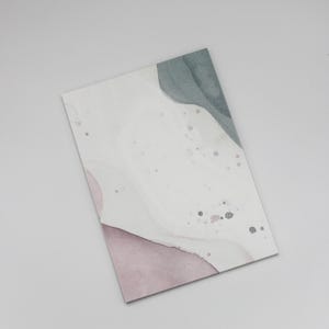 Könnte beinhalten: Rechteckiger Kunstdruck mit einem Aquarelldesign. Der Druck zeigt weiche, abstrakte Formen in gedämpften Tönen von Weiß, Staubrosa und Salbeigrün. Kleine graue Sprenkel verleihen dem Design Textur und schaffen eine moderne und minimalistische Ästhetik.