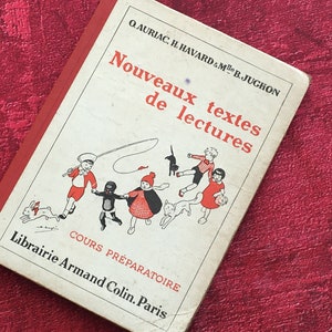 May include: A vintage book titled "Nouveaux textes de lectures" by Q. AURIAC, H. HAVARD & Me B. JUCHON. The book cover features a colorful illustration of children playing with a cat and a rabbit.
