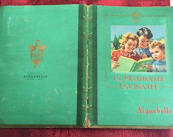 May include: A green book cover with the title "La Promenade Enchantée" and the text "Collection du Chocolat Aiguebelle". The cover features an illustration of three children reading a book together.