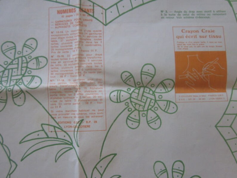 May include: A white and green patterned paper with a section of text in French. The text includes the words "NUMEROS GRANTS" and "Crayon Craie qui ecrit sur tissu".