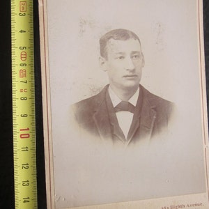 Peut inclure: Une photographie en noir et blanc d'un homme en costume et cravate. La photo est encadrée d'un bord blanc avec le texte "O'Connor, Portraits" et "283 Eighth Avenue, Bet. 24th & 25th Sts. NEW YORK." imprimé sous l'image.
