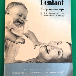 Peut inclure: Une couverture de livre vintage avec une photo en noir et blanc d'un bébé touchant le visage d'une femme. Le titre du livre est "L'enfant du premier âge la naissance et les 2 premières années" et le texte ci-dessous indique "EDITE POUR LE COMPTE DE LA FEDERATION NATIONALE DES ORGANISMES DE SECURITE SOCIALE".