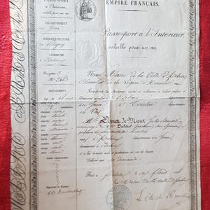 Peut inclure: Un passeport intérieur français ancien datant de l'Empire Français. Le document en papier blanc cassé présente des textes imprimés en noir, des inscriptions manuscrites en cursive et des bordures décoratives, avec des sceaux et signatures.
