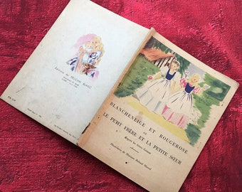 May include: A vintage children's book titled "Blancheneige et Rougerose et Le Petit Frere et La Petite Soeur" with illustrations of two girls in dresses and a cottage in the background.