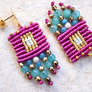 May include: A pair of pink and gold earrings with turquoise and white beads. The earrings are made with a knotted cord technique and have a tassel-like design.