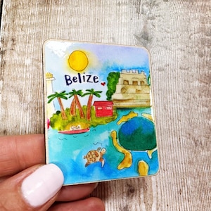 May include: A colourful square magnet featuring a watercolour illustration of Belize. The design includes a sun, palm trees, a lighthouse, a red building, a turtle, and the word "Belize".