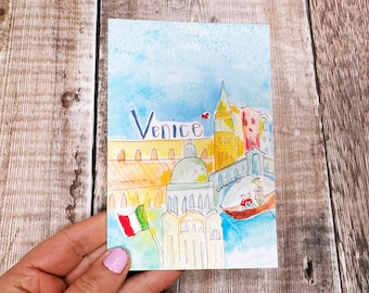 May include: Watercolor painting of Venice with the word "Venice" in blue script. The artwork depicts buildings, a gondola, and an Italian flag. The color palette includes blue, yellow, orange, and red.