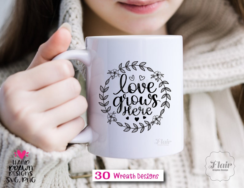 K&ouml;nnte beinhalten: Eine wei&szlig;e Keramiktasse mit einem schwarzen floralen Kranzdesign und dem Text "love grows here".