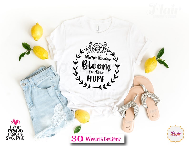 K&ouml;nnte beinhalten: Wei&szlig;es T-Shirt mit einem schwarzen Kranz-Design, auf dem "Wo Blumen bl&uuml;hen, bl&uuml;ht auch Hoffnung" steht.