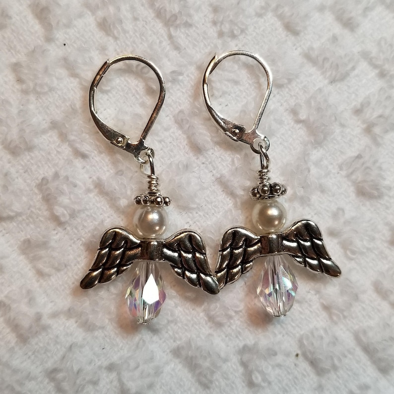 May include: Silver angel wing earrings with a white pearl and a clear crystal dangle.
