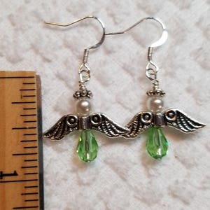 May include: Silver angel wing earrings with green crystal drops and white pearl accents.