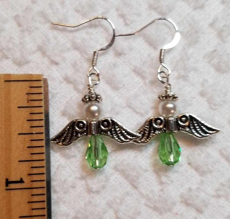 May include: Silver angel wing earrings with green crystal drops and white pearl accents.