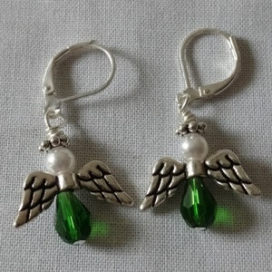 May include: A pair of silver angel earrings with green crystal accents and white pearl beads.