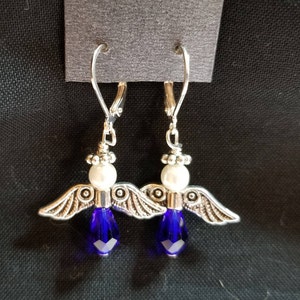 May include: Silver angel wing earrings with a white pearl and a dark blue crystal dangle.