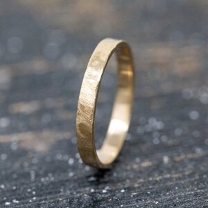 May include: A simple gold band ring with a hammered texture.