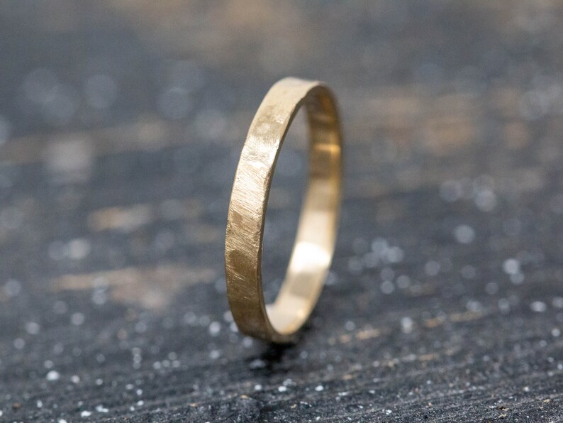 May include: A simple gold band ring with a hammered texture.
