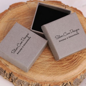 May include: Two gray boxes with the text "Silver Cave Designs Everyday is Extraordinary" printed on them. The boxes are made of cardboard and have a matte finish.