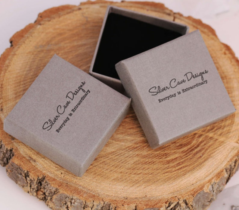 May include: Two gray boxes with the text "Silver Cave Designs Everyday is Extraordinary" printed on them. The boxes are made of cardboard and have a matte finish.