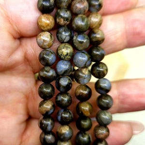 Könnte beinhalten: Ein Set aus vier Perlenarmbändern mit braunen, schwarzen und blauen gesprenkelten Perlen.