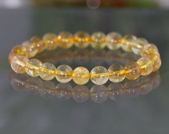 May include: A bracelet made of round, translucent yellow beads. The beads are strung together on a clear elastic cord.