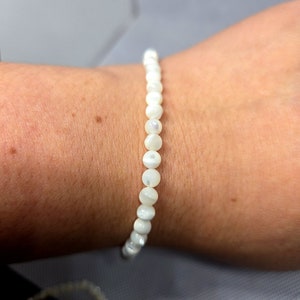 May include: A white pearl bracelet with a simple design. The bracelet is made of small, round pearls that are strung together on a thin string.
