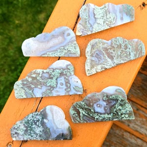 May include: Five green and white agate cloud shaped stones. The stones are polished and have a natural, organic look.