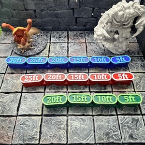 Op de afbeelding: Drie rijen kleurrijke afstandsaanduidingen voor tabletop gaming. De bovenste rij is blauw, de middelste rij is rood en de onderste rij is groen. Elke marker geeft afstanden in voet weer, vari&euml;rend van 5ft tot 30ft.