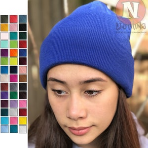 May include: A royal blue beanie made of knitted fabric. The beanie is worn by a person with long brown hair.