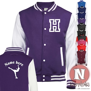 以下が含まれることがあります： 紫と白のベースボールジャケット。前面に白いHの文字、背面に白いフィギュアスケーターが描かれています。背面には「Name here」の文字も書かれています。