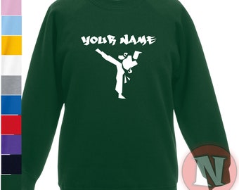 Puede incluir: Una sudadera verde oscuro con una silueta blanca de una persona dando una patada de karate. El texto "YOUR NAME" está impreso en blanco sobre la silueta.