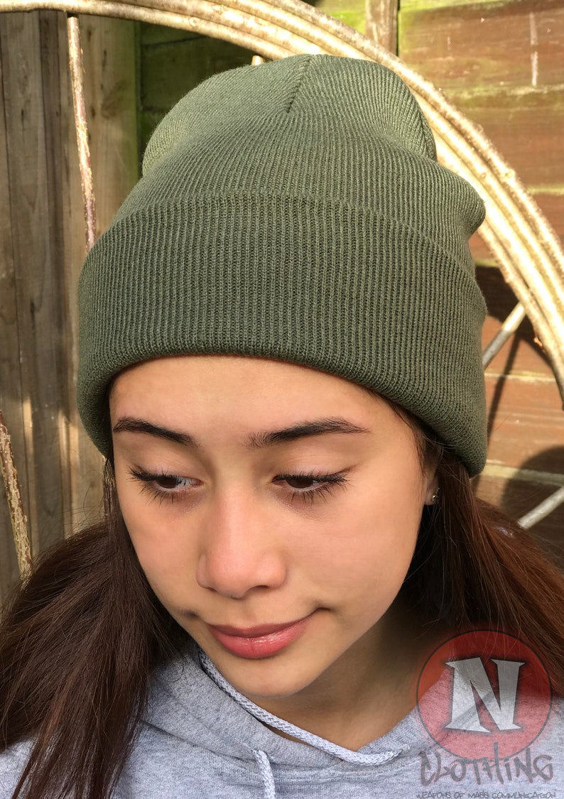 May include: A green knitted beanie hat. The hat is made of a soft, comfortable material and has a simple, classic design.