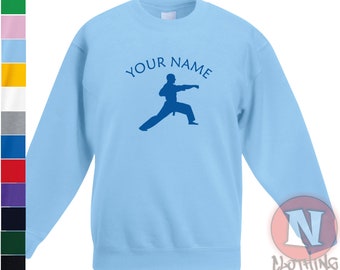 Puede incluir: Sudadera azul claro con una silueta azul de una persona en una pose de artes marciales. El texto "YOUR NAME" está impreso sobre la silueta.