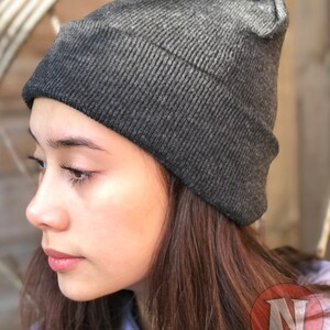 May include: A dark gray beanie with a ribbed texture. The beanie is made of a soft, comfortable material.